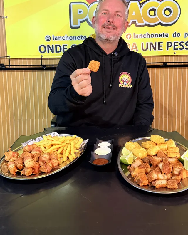 O Polaco à mesa com porções de batata frita, frango e torresmo